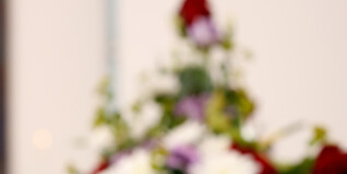 A bouquet of flowers, slightly out of focus, placed on the lid of a white casket.