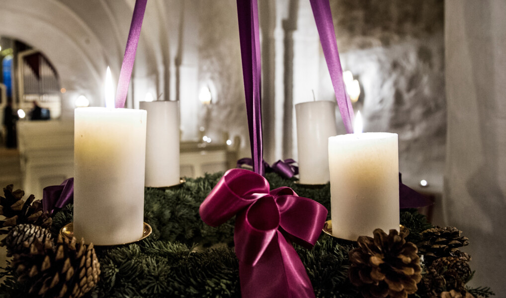 En adventskrans med lilla bånd i en lille middelalderkirke